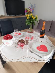 a table with a white table cloth with a bottle of wine at Domek pod lipami in Dwikozy