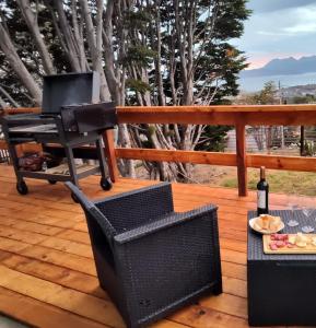 a grill on a deck with a plate of food and a bottle of wine at Casa de Ushuaia in Ushuaia