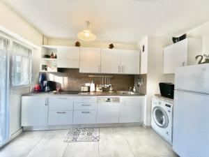 a kitchen with white cabinets and a washer and dryer at Arènes by Welcome to Cannes in Cannes