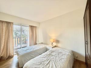 two beds in a room with a window at Arènes by Welcome to Cannes in Cannes