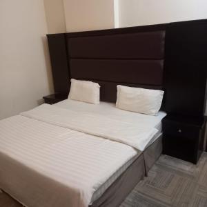 ein Bett mit einem schwarzen Kopfteil und zwei weißen Kissen in der Unterkunft حكاية ليل للشقق الفندقية in Ha'il