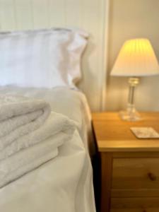 un letto con lenzuola bianche e una lampada su un comodino di Vast, Elegant Home with Indoor Pool & Sauna near Popular Golf Course a Kington