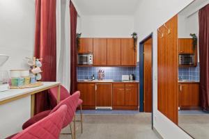 una pequeña cocina con armarios de madera y sillas rojas en Central - 30 m² - Next to Augarten, en Viena