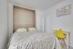 1 dormitorio con cama, escritorio y silla amarilla en Chic studio near Paris en Colombes