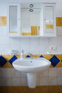 W łazience znajduje się biała umywalka i lustro. w obiekcie Sardinia's house IUN R5500 w mieście Gonnesa