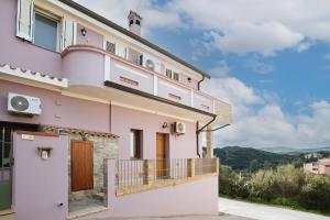 a pink house with a balcony and mountains in the background at Sardinia's house IUN R5500 in Gonnesa