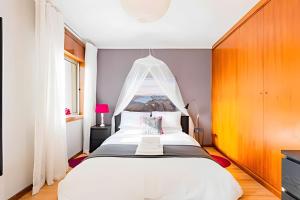 a bedroom with a large white bed with a canopy at Stunning View Apartament by BnbHost in Vila Nova de Gaia