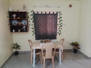 mesa y sillas en una habitación con ventana en shanthi home, en Puttaparti