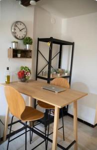 einem Holztisch mit zwei Stühlen und einer Uhr an der Wand in der Unterkunft Appartement cœur du centre-ville in Avignon