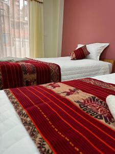 Habitación con 2 camas y mantas rojas y blancas. en LA CASA REAL en Puno
