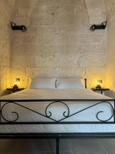 a bedroom with a white bed with two tables at Le Pietre Apartments in Ostuni