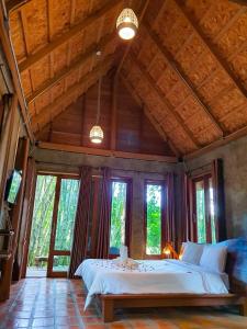 ein Schlafzimmer mit einem großen Bett in einem Zimmer mit Fenstern in der Unterkunft Kung Nok Tha Resort Nakhon Si Thammarat in Nakhon Si Thammarat