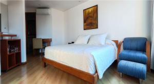 a bedroom with a bed and a blue chair at Hotel Casa Victoria in Medellín