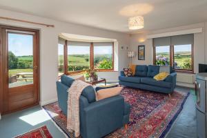 a living room with two blue couches and a rug at Coastal Bungalow Near Marloes with Log Burner and Garden in Dale
