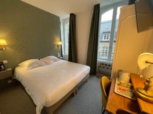 a bedroom with a bed and a desk and a window at Balzac Hôtel in Fougères