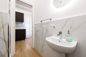 La salle de bains blanche est pourvue d'un lavabo et d'un miroir. dans l'établissement APPARTAMENTI VALLETTI ERCOLANO, à Ercolano