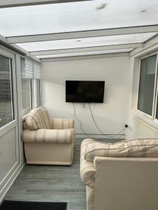 sala de estar con 2 sofás y TV de pantalla plana en BG Homes, en Peterborough