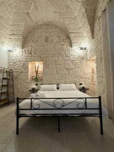 1 dormitorio con 1 cama en una pared de piedra en Le Pietre Apartments, en Ostuni