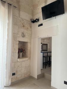 sala de estar con TV en una pared de piedra en Le Pietre Apartments, en Ostuni