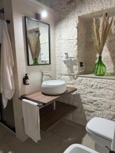 baño con lavabo blanco y pared de piedra en Le Pietre Apartments, en Ostuni