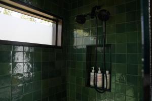 - une douche carrelée verte avec 2 bouteilles de shampoing dans l'établissement Tofte Trails, à Tofte