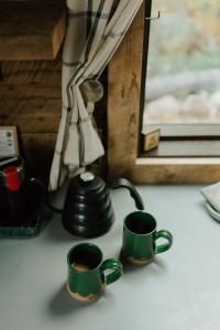 dos tazas de café verdes sentadas sobre una mesa en Tofte Trails en Tofte