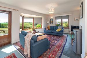 ein Wohnzimmer mit zwei blauen Sofas und einem Teppich in der Unterkunft Coastal Bungalow Near Marloes with Log Burner and Garden in Dale