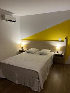 ein Schlafzimmer mit einem großen Bett mit gelber Wand in der Unterkunft Mova Express Hotel - CAMPINAS in Campinas