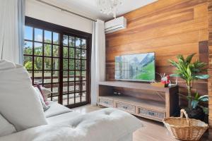 uma sala de estar com uma televisão de ecrã plano numa parede de madeira em Apartamento 4 Dorm e Piscina by Achei Gramado em Gramado