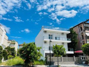 Un edificio blanco con un cielo azul al fondo. en ApartHotel Villa Eva 2 bedroom, en Olympiakí Aktí