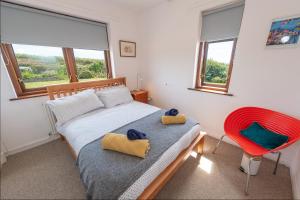 a bedroom with a bed and a red chair at Coastal Bungalow Near Marloes with Log Burner and Garden in Dale
