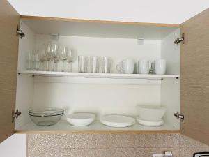 un armario lleno de tazones, platos y vasos en ApartHotel Villa Eva 2 bedroom, en Olympiakí Aktí