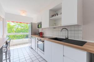 a white kitchen with a sink and a window at Spacious 3 bedroom apartment & private parking! in Lambersart
