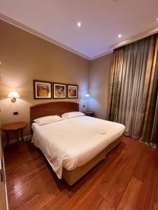 1 dormitorio con 1 cama blanca grande y suelo de madera en LH Hotel Lloyd Roma, en Roma