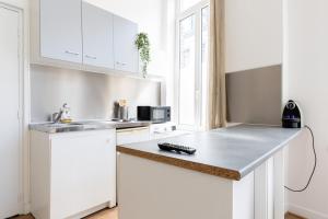 eine Küche mit weißen Schränken und einer Arbeitsplatte in der Unterkunft Functional flat close to the station in Lille + 11 Fotos