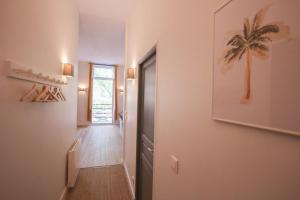 un pasillo con una puerta a una habitación con una pintura de palmera en 2-bedroom flat + private car park., en Lille