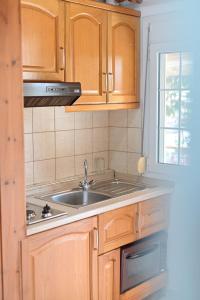 una cocina con armarios de madera y fregadero en Guesthouse Agnandi, en Kato Loutraki