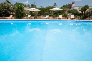 una grande piscina blu con sedie e ombrelloni di Villa Palmizi a Ruffano