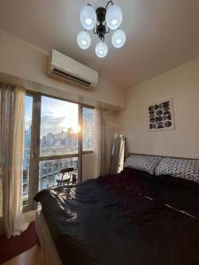 ein Schlafzimmer mit einem Bett und einem großen Fenster in der Unterkunft Cozy Skyline View Unit at Acqua @Livingstone in Manila