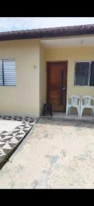 une maison avec deux chaises blanches et une porte dans l'établissement Casa Relax, à Caraguatatuba
