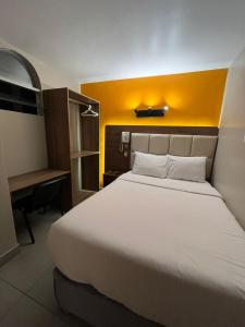 1 dormitorio con 1 cama grande y pared amarilla en Hotel Residencial Alfa, en Lima