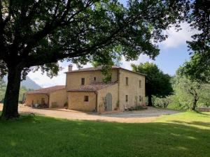 een groot huis met een boom ervoor bij Podere Montaione in Volterra