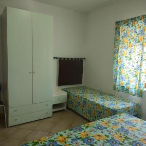- une chambre avec deux lits, une armoire et une fenêtre dans l'établissement Portoghesi Apt, à Àrbatax