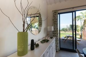 蓬塔德爾加達的住宿－Batalha Golf Villas & Spa，一个带镜子的房间的花瓶,有枝子