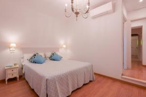 a white bedroom with a bed with blue pillows at Baco B&B in Cagliari