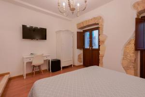 a bedroom with a bed and a desk and a television at Baco B&B in Cagliari