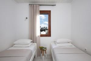 two beds in a room with a window at Acroterra - Easy Living in Alyki