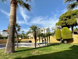 un parc avec des palmiers et une maison blanche dans l'établissement Bonito Apartamento Con Piscina y Jacuzzi, à L'Alfàs del Pi