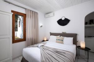 a bedroom with a bed with white sheets and a window at Acroterra - Easy Living in Alyki