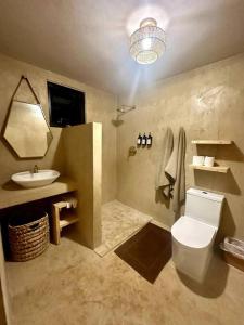 a bathroom with a white toilet and a sink at VillaMaya- Hidden City Oasis in Mayaguez